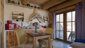 Una habitación acogedora con muebles de madera, una mesa de comedor y un amplio ventanal con cortinas.