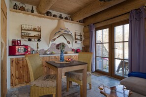 Ein gemütliches Zimmer mit Holzmöbeln, einem Esstisch und einem großen Fenster mit Vorhängen.
