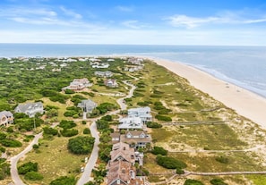 Ein Luftbild einer Küstenwohngegend mit Häusern, einem Strand und blauem Himmel.