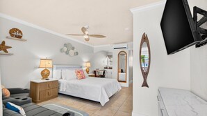 A bedroom with a bed, a desk, a chair, a TV, and a bathroom. - Coconut Villas Suite 5 (Redington Shores)