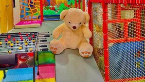 A play area with a foosball table, a large teddy bear, and a colorful mural.