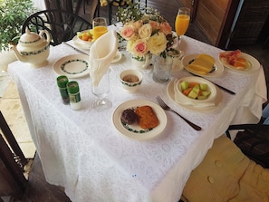 A table set with plates of food, a teapot, a pitcher, a glass of orange juice, and a vase of flowers. - Peaceful king bed guestroom with AC close to Curacao International Airport (Mahuma)
