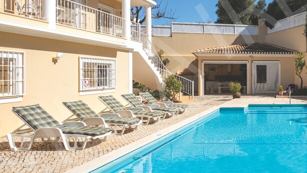 A multi-story building with a swimming pool, sun loungers, and a covered patio area. - VILLA IRLANDAIS (Alvor)