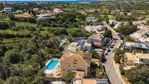 An aerial view of a residential area with houses, a swimming pool, and a road. - VILLA IRLANDAIS (Alvor)