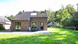 A small brick house with a tiled roof, a front door, and a patio with outdoor furniture. - Serene Ewijk Abode by the Lake (Ewijk)