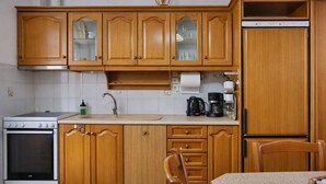 A kitchen with wooden cabinets, a stove, a sink, and a refrigerator. - Matroni s House - Seafront Getaway in Monemvasia (Monemvasia)