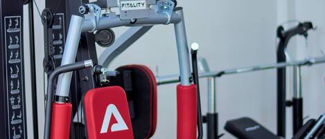 A gym with red and black equipment, including a bench and a cable machine.