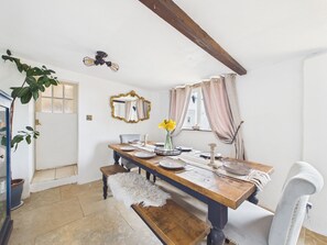 A dining area with a wooden table, chairs, a bench, a mirror, and a ceiling fan. - Tor Farm (Camelford)