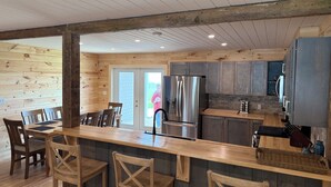 Ein Holzinterieur mit Küchenzeile, Barhocker und Esstisch.