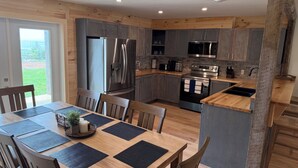 Eine moderne Küche mit grauen Schränken, Edelstahlgeräten und einem Essbereich mit Holztisch und -stühlen.