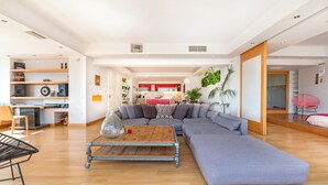Una sala moderna con un sofá seccional, una mesa de centro y un comedor al fondo.