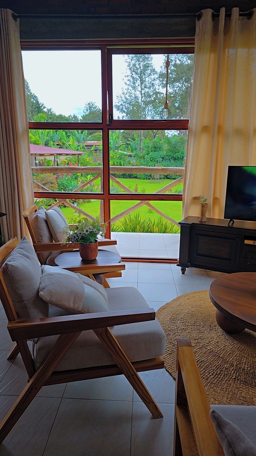 A room with a large window, a sofa, a TV, and a small table with a plant.