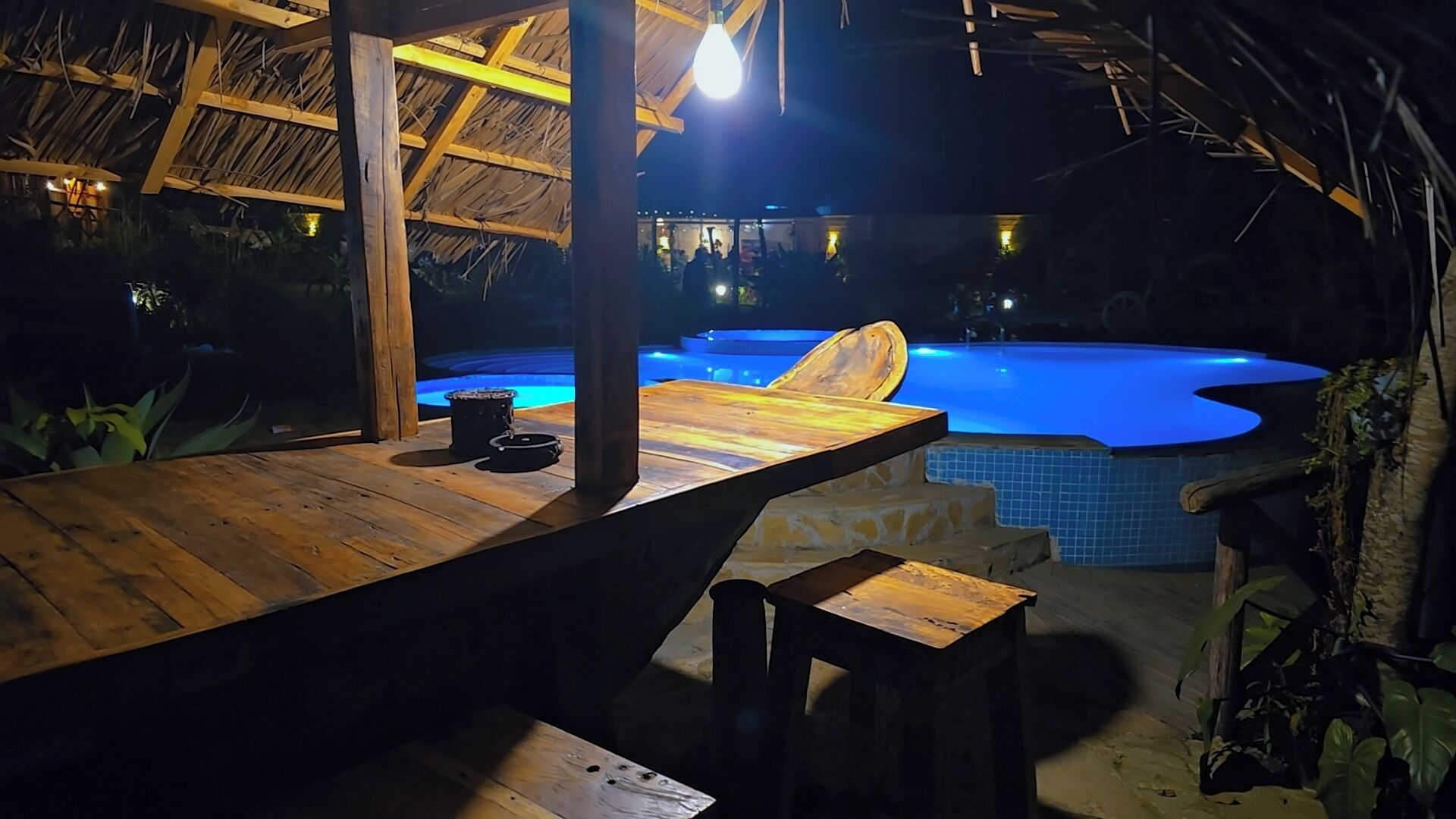 An outdoor pool area with a wooden deck, a chair, and a table.