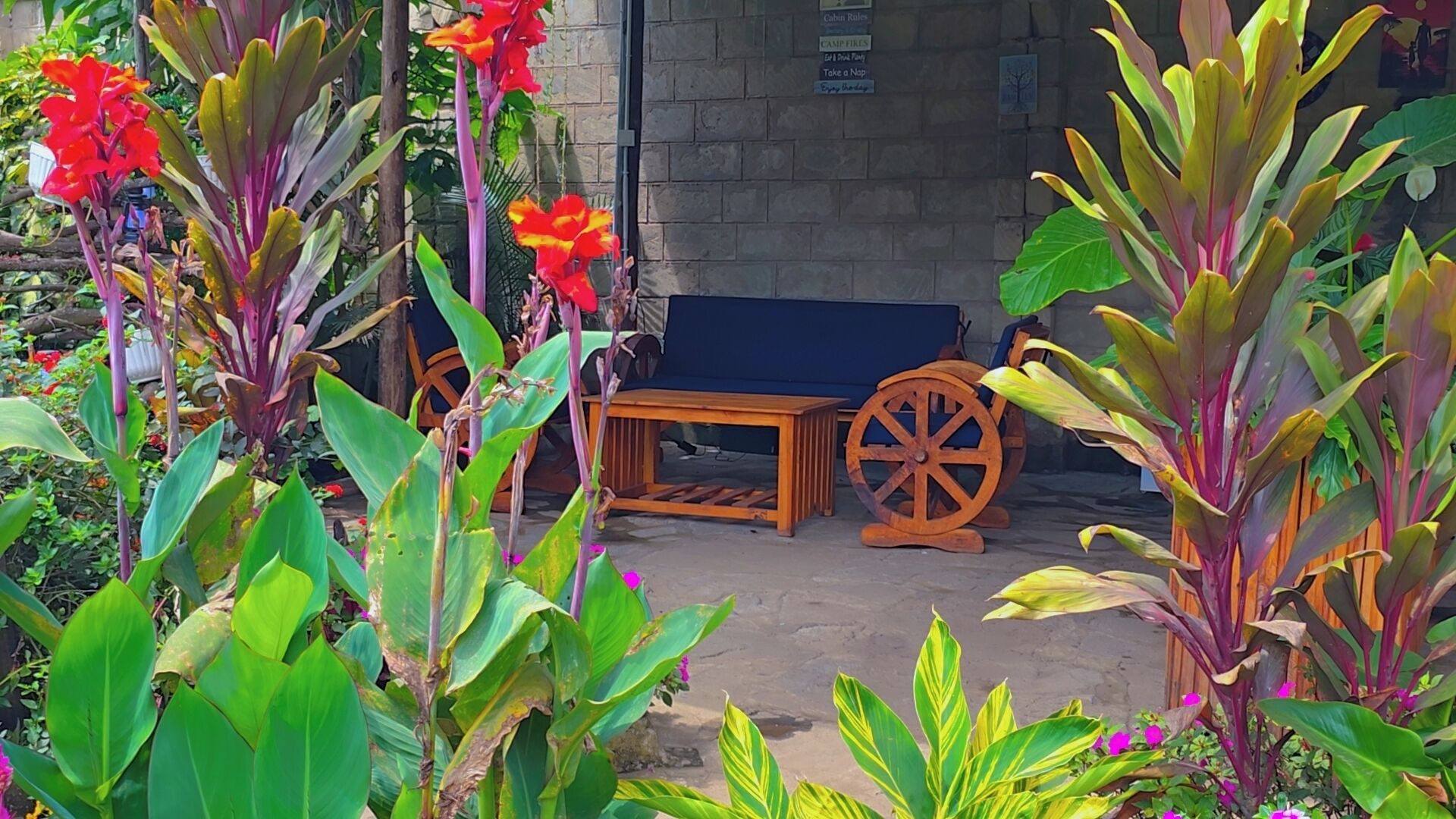 Un jardín con un banco de madera, una mesa de madera y una gran rueda de madera.