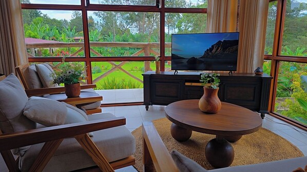 Ein Zimmer mit großem Fenster, Fernseher, Sofa, Couchtisch und Schrank.