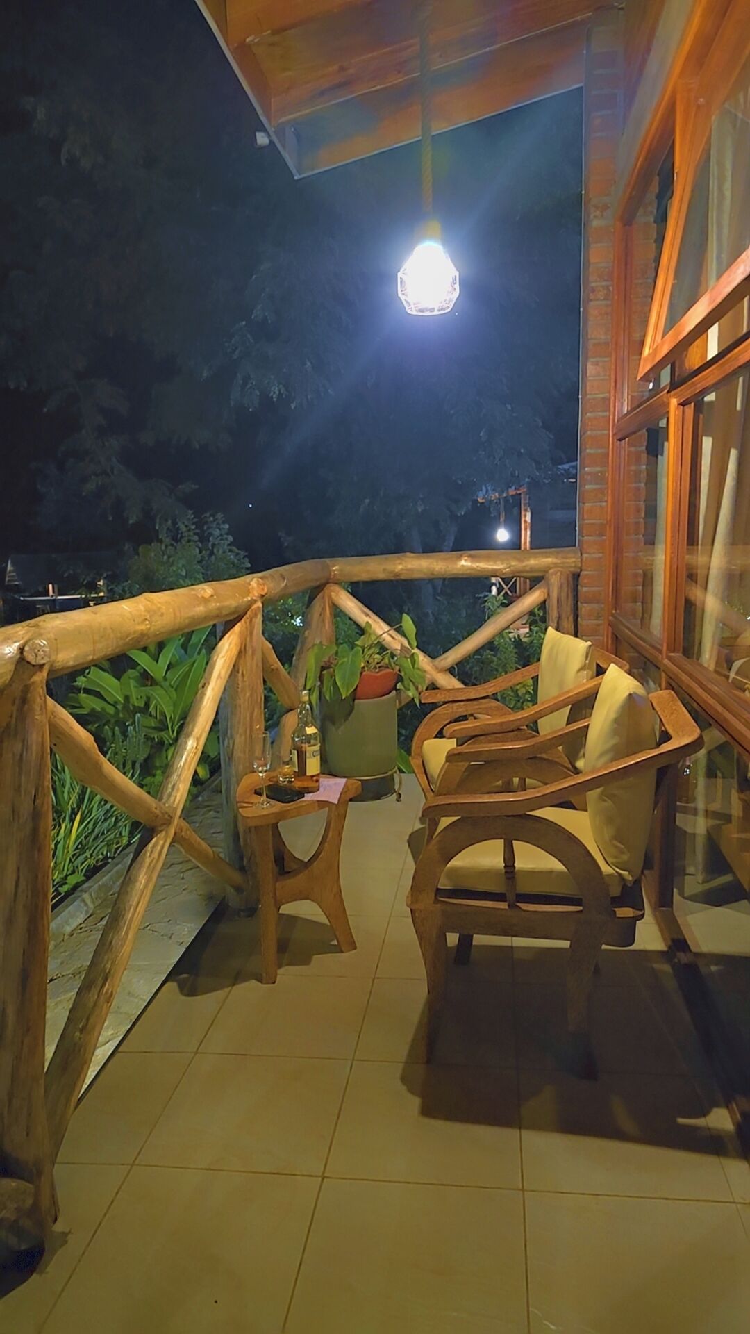 A wooden deck with a railing, a table with chairs, and a hanging light fixture.