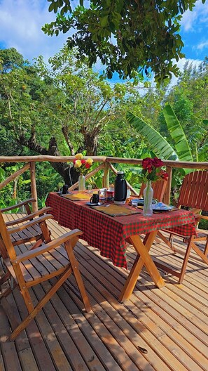Eine Holzterrasse mit kariertem Tischläufer, Holzkästen und einem für eine Mahlzeit gedeckten Tisch.