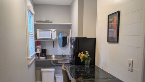 Una cocina moderna con encimera de mármol negro, un refrigerador, un microondas y un lavaplatos.