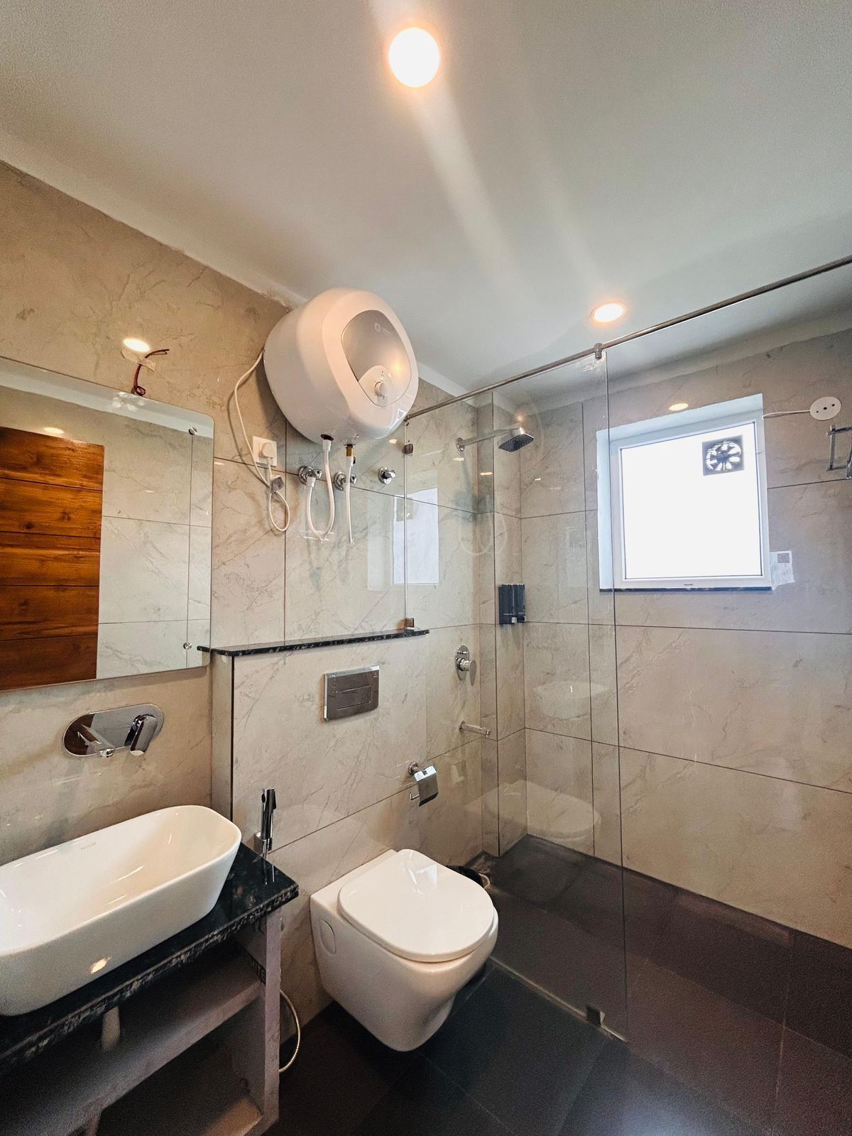 Casa de banho moderna com cabine de duche em vidro, sanita branca, lavatório e espelho.