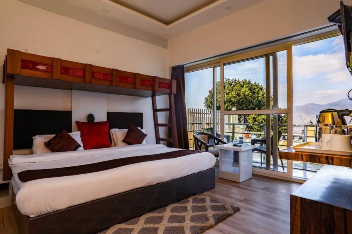 A modern hotel room with a large bed, a small desk, and a balcony with a view.