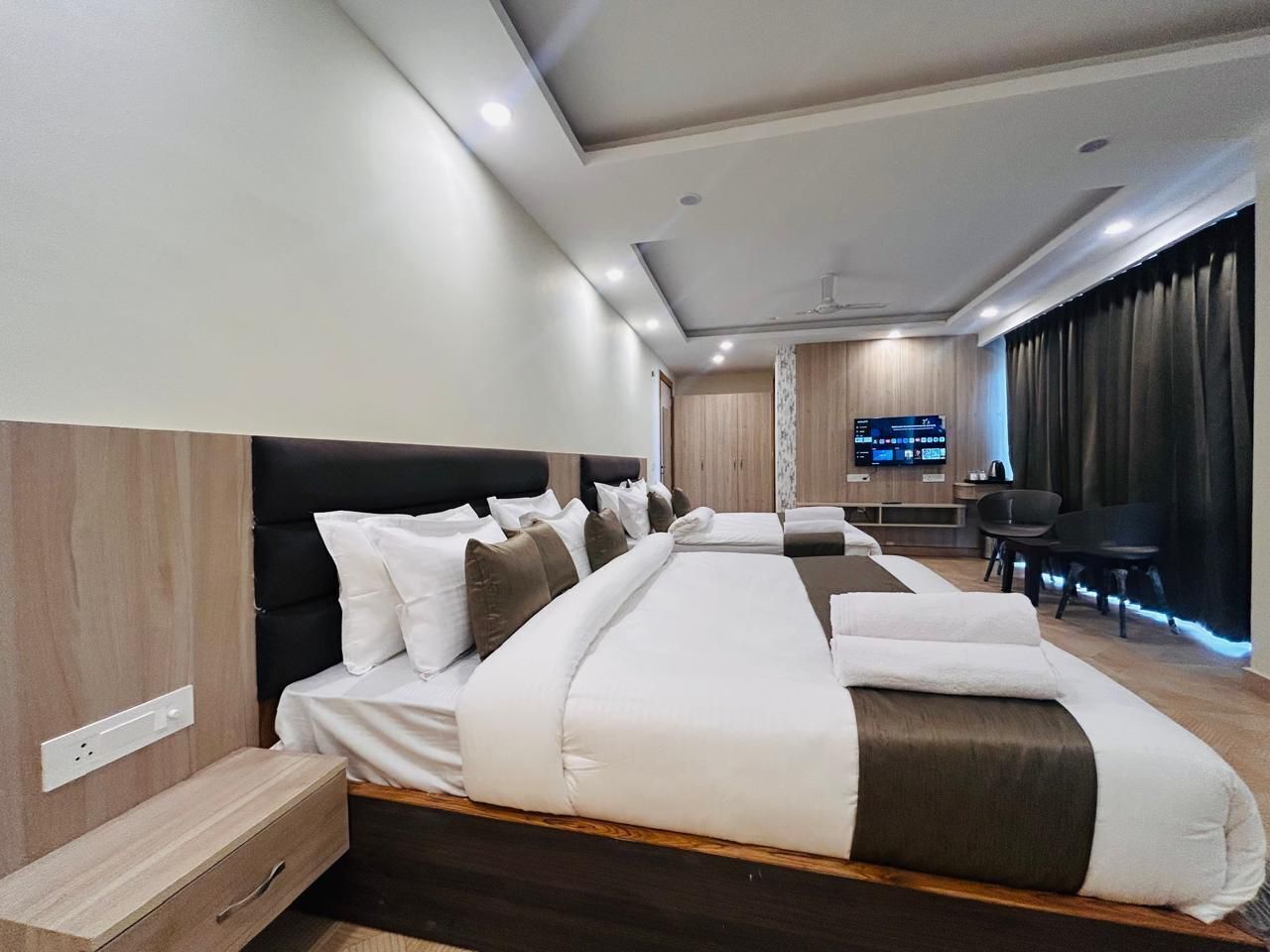 A modern hotel room with a large bed, a desk, a chair, and a television.