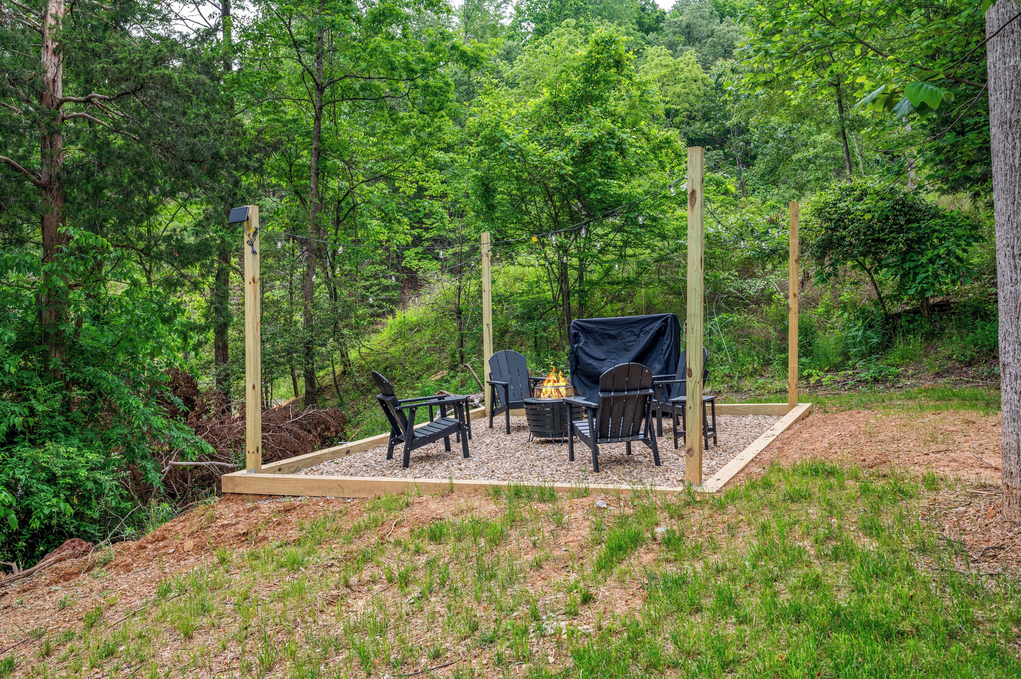 A forested outdoor area with a fire pit and seating.