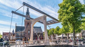 A historic bridge with a pedestrian walkway, a canal, and a building with a tower in the background. - Modern Chalet With 2 Bathrooms (West-Graftdijk)