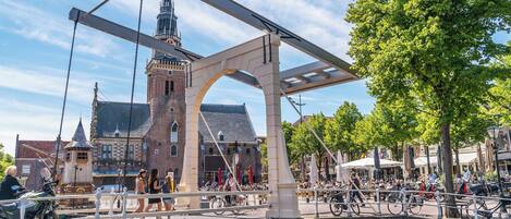 Een historische brug met een toren, een gracht en een levendig caféterras.