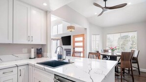 Una cocina moderna con armarios blancos, encimera de mármol y lavavajillas integrado.