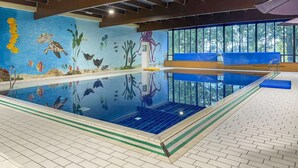 An indoor swimming pool with a mural of marine life, a bench, and a view of trees through large windows. - Lakeside Sauna Bungalow for 4 (Ewijk)