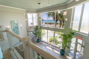Eine Hotellobby mit Blick auf den Strand, Zimmerpflanzen und einer Treppe.