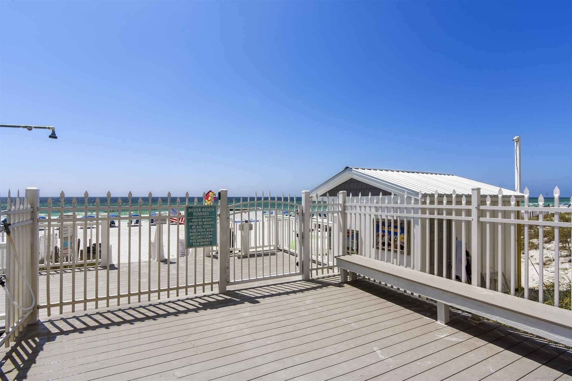 Une terrasse en bois avec une clôture blanche donnant sur une plage.
