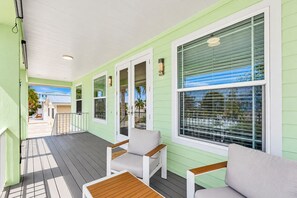 A covered porch with a wooden deck, light-colored walls, and large windows with blinds. - 140 Pearl Paradise 3br/2ba W/ Pool! 3 Bedroom Home (Fort Myers Beach)