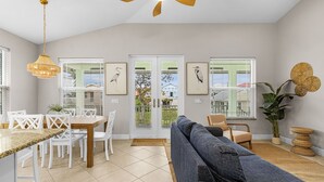 Una sala de estar moderna con comedor, ventilador de techo y obras de arte en las paredes.