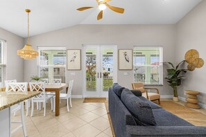 Ein modernes Wohnzimmer mit Essbereich, Deckenventilator und Kunstwerken an den Wänden.