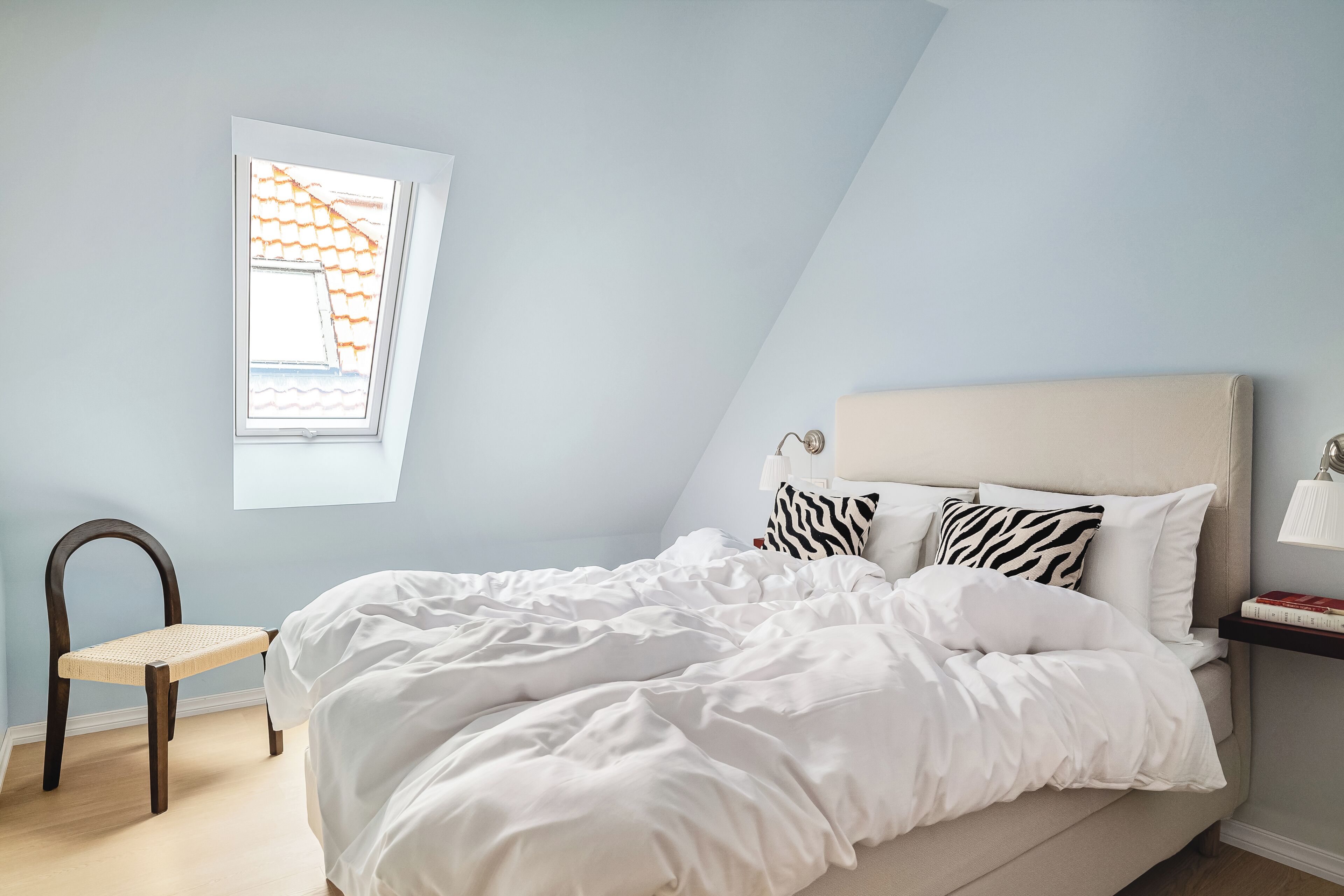 Un dormitorio con una cama, una ventana con vistas, una silla y una mesita de noche.
