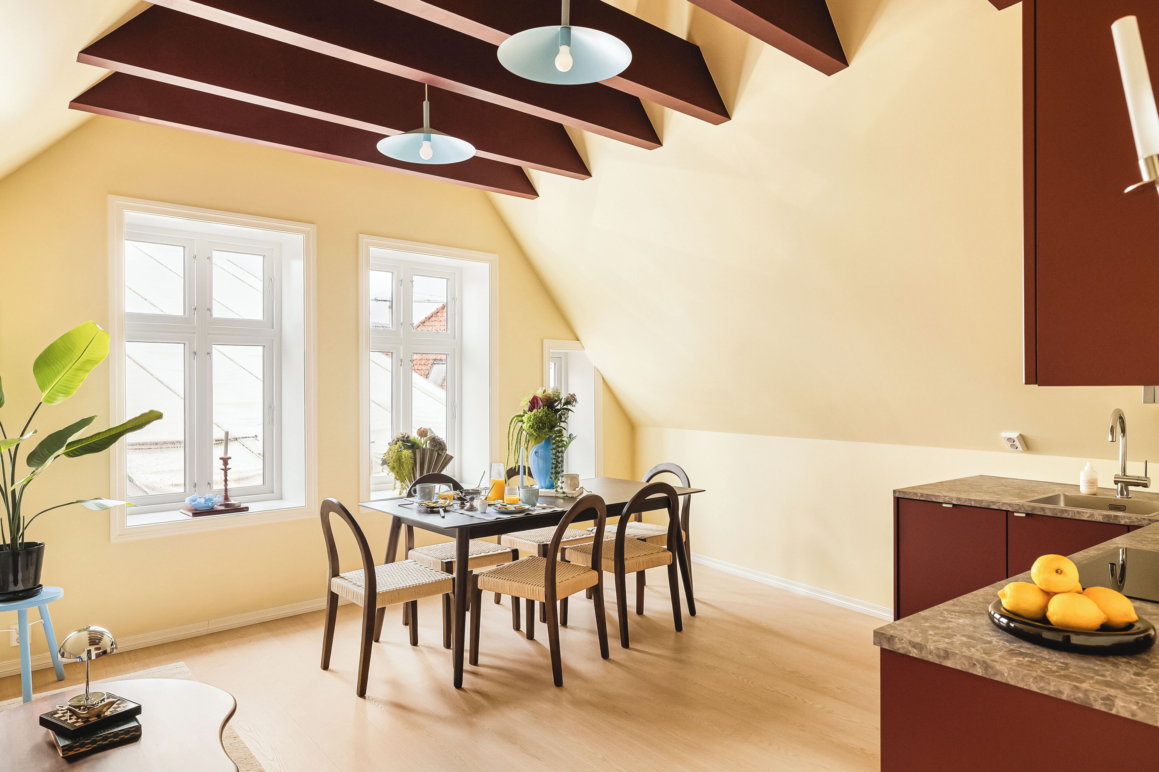 A dining area with a table, chairs, and a kitchen counter with lemons.