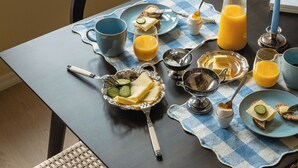 Una mesa de desayuno dispuesta con platos, tazas y un frutero.