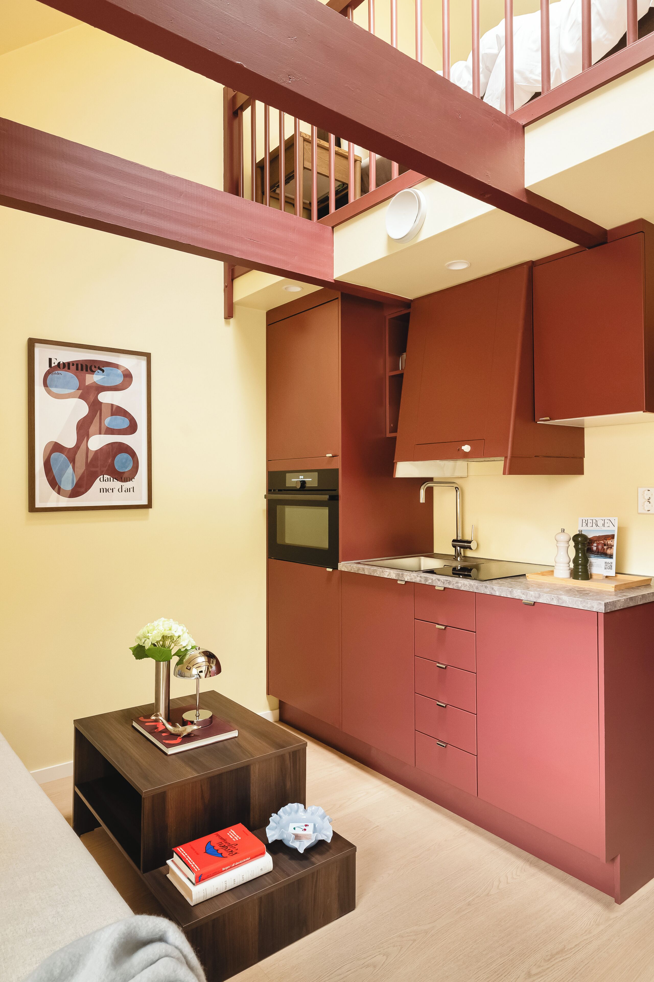 Eine moderne Küche mit Holzausbau, einem Einbauofen und einer kleinen Kochinsel mit Spüle.