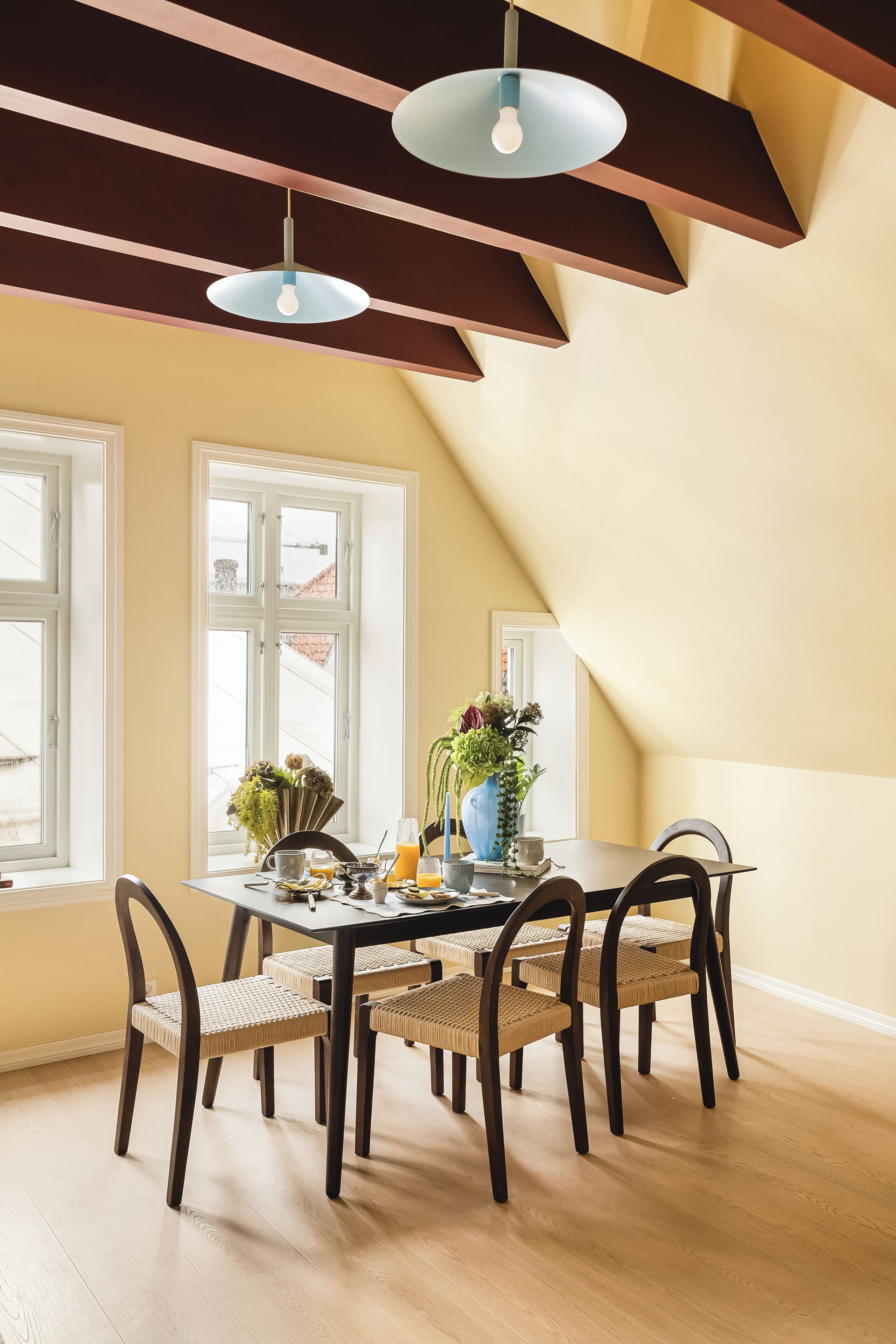 A dining area with a table, chairs, and hanging pendant lights.