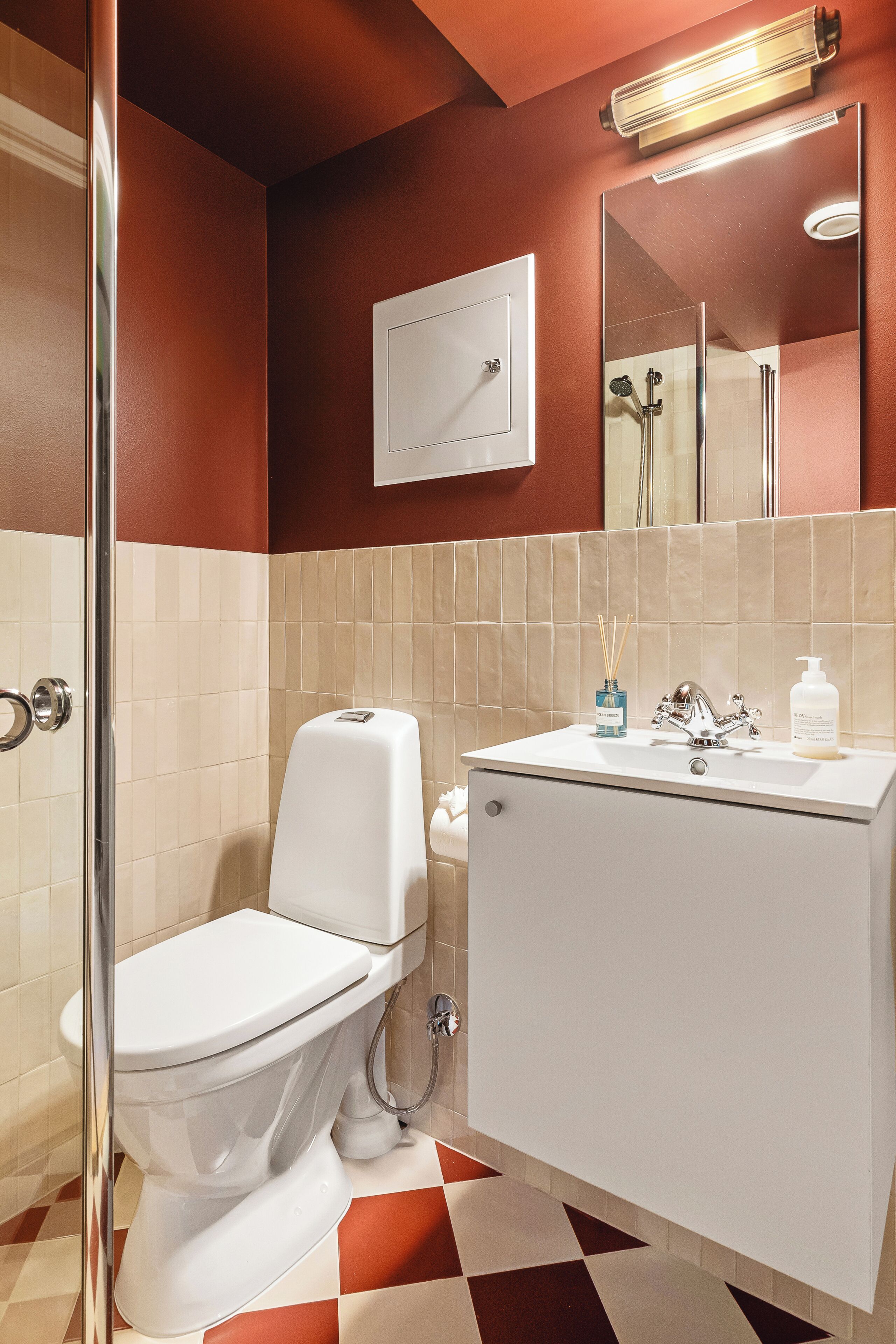 A bathroom with a toilet, sink, mirror, and shower.