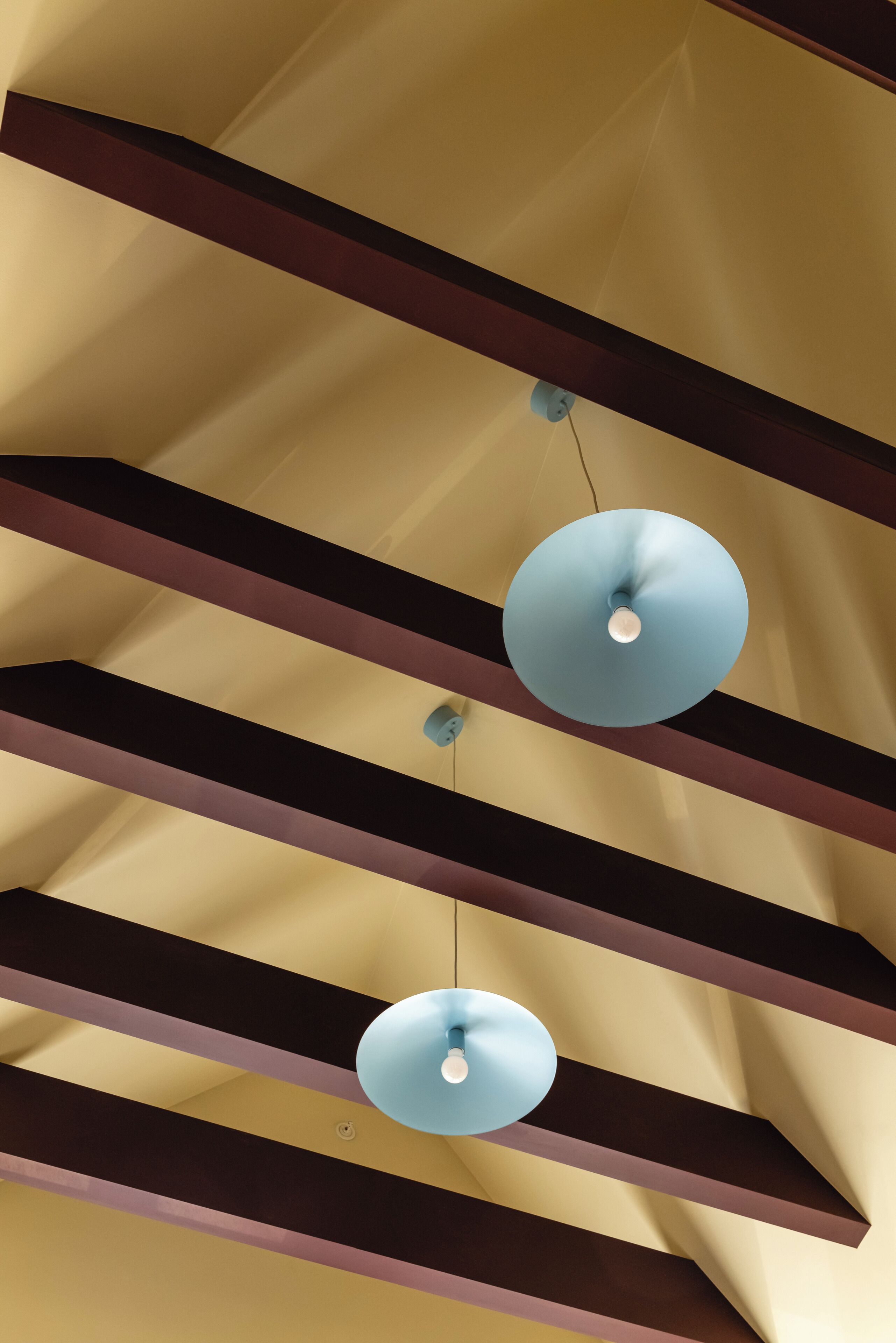 Un soffitto con travi orizzontali e lampade a sospensione.