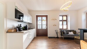 A modern kitchen with white cabinets, a built-in oven, and a wooden countertop. - Vita Aurum Elbe-Apartments Neustadt  (Dresden)