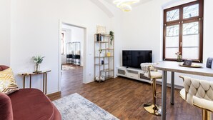 A modern living room with a TV, bar area, and a dining table. - Vita Aurum Elbe-Apartments Neustadt  (Dresden)
