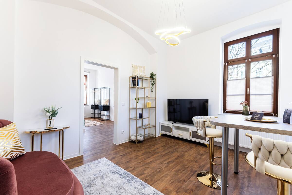 A modern living room with a TV, bar area, and a dining table.