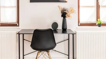 A modern room with a black desk, a black chair, a large abstract painting, and a window with blinds.