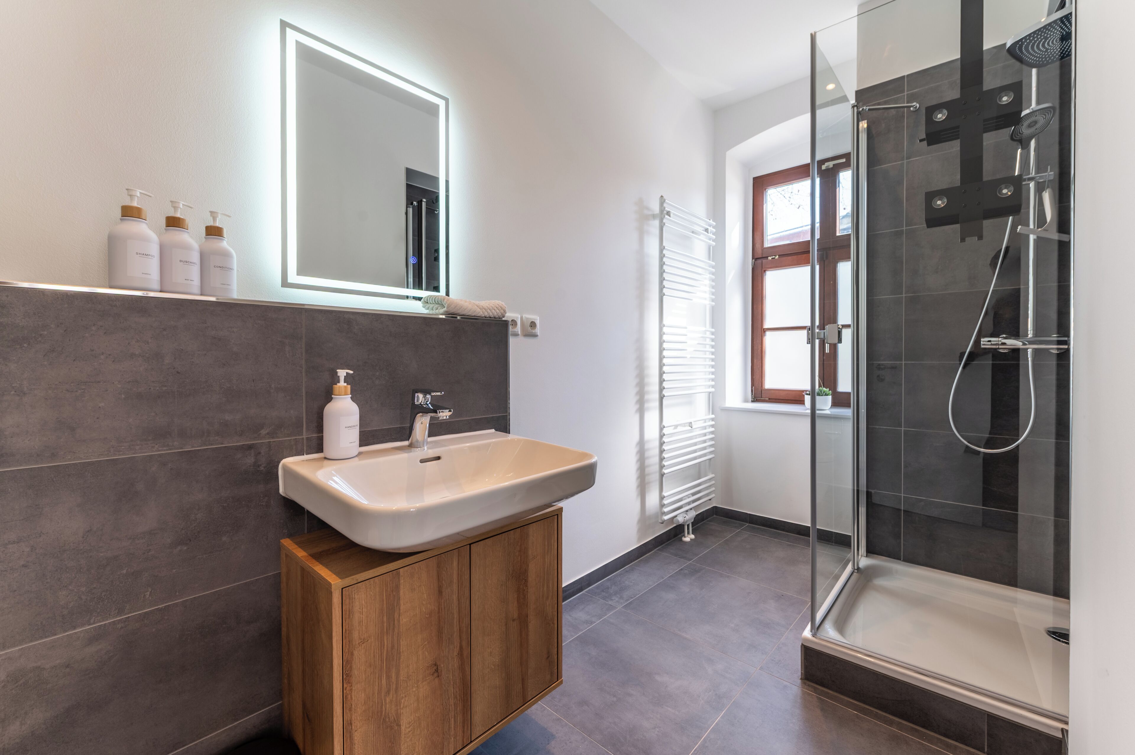Une salle de bain moderne avec un lavabo, un miroir et une douche.