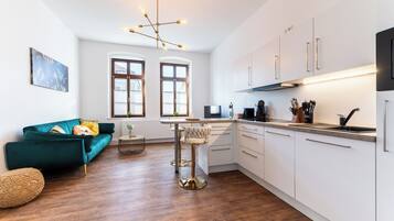 Una cucina moderna con mobili bianchi, uno sgabello da bar e un tavolo da pranzo.