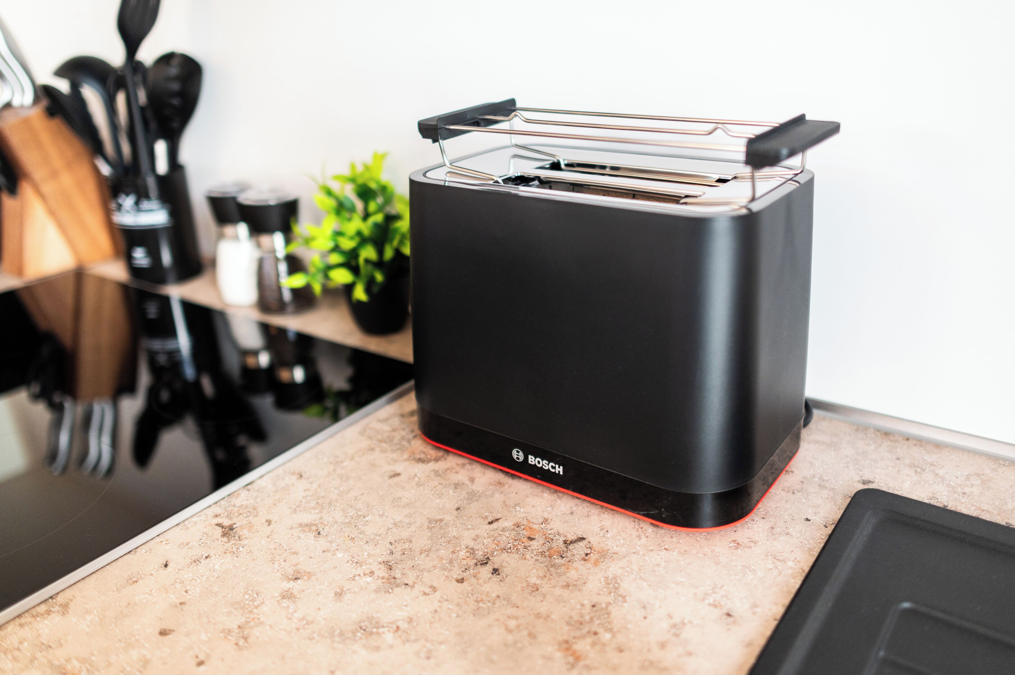 Eine Küche mit einem schwarzen Toaster auf der Arbeitsfläche, einer Kaffeemaschine und einer Pflanze.