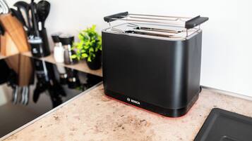 Eine Küche mit einem schwarzen Toaster auf der Arbeitsfläche, einer Kaffeemaschine und einer Pflanze.